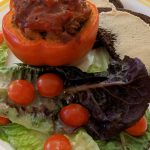 red stuffed pepper with a lettuce salad, cherry tomatoes, and pumpernickel toast